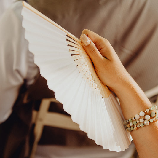 Invitée de mariage tenant un éventail blanc